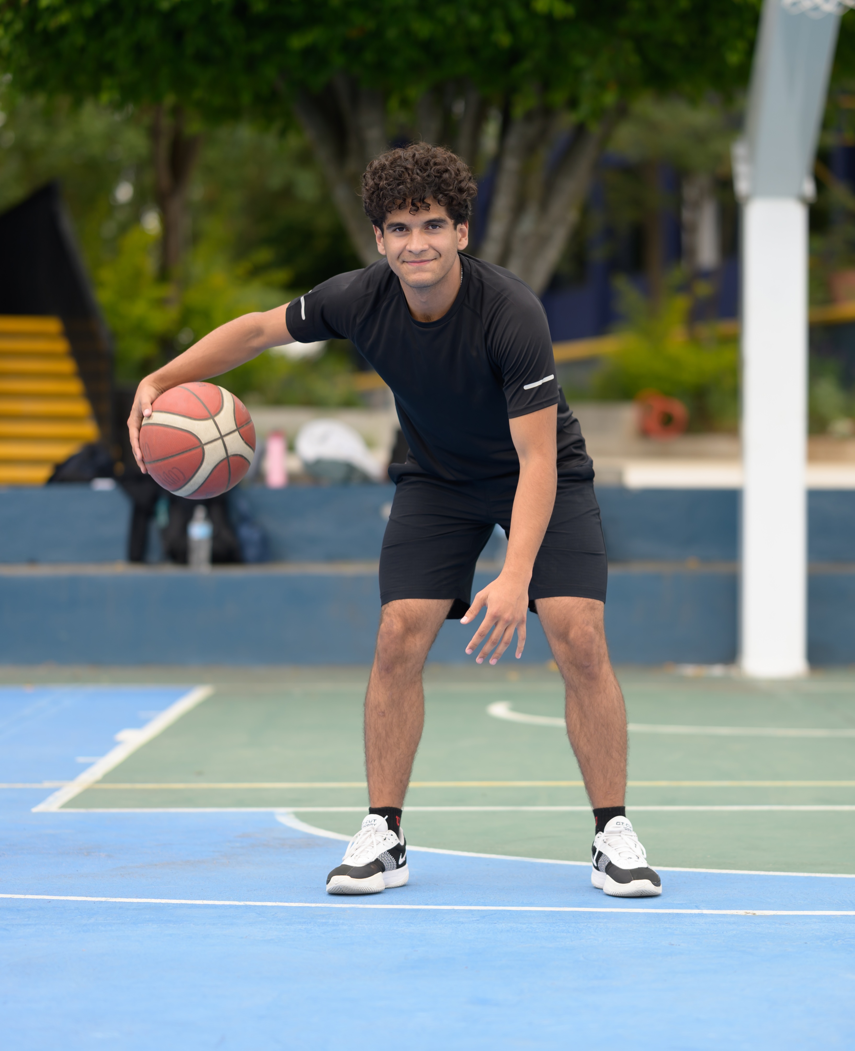 Estudiante botando un balón de baloncesto en la cancha del campus