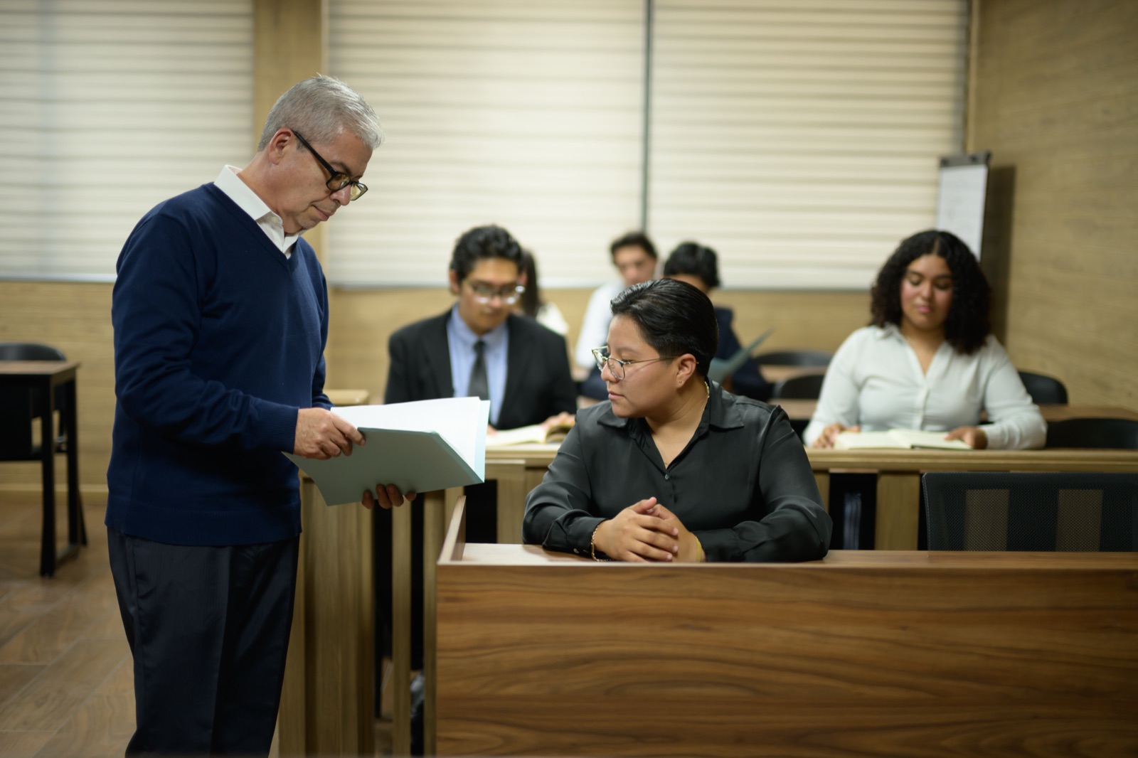 Profesor revisando un documento con estudiantes en la sala de juicios orales