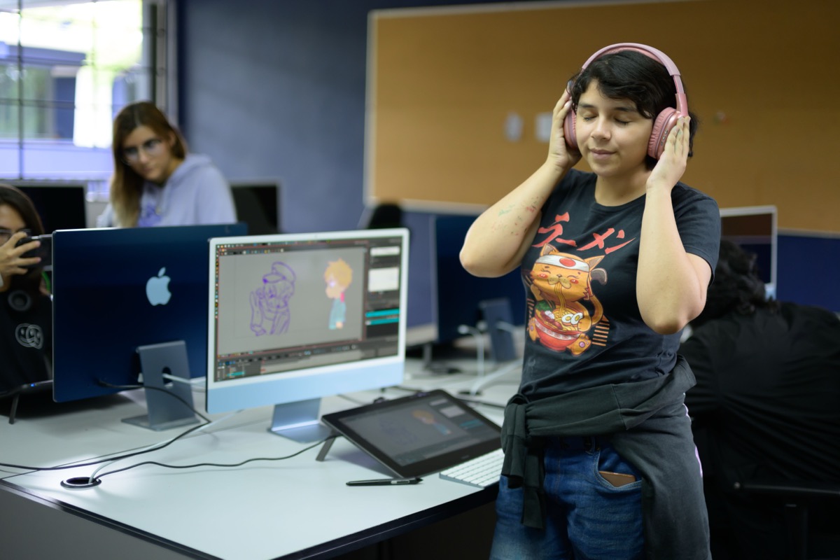 Estudiante de UMValla editando con audifonos frente a su estacion de trabajo.