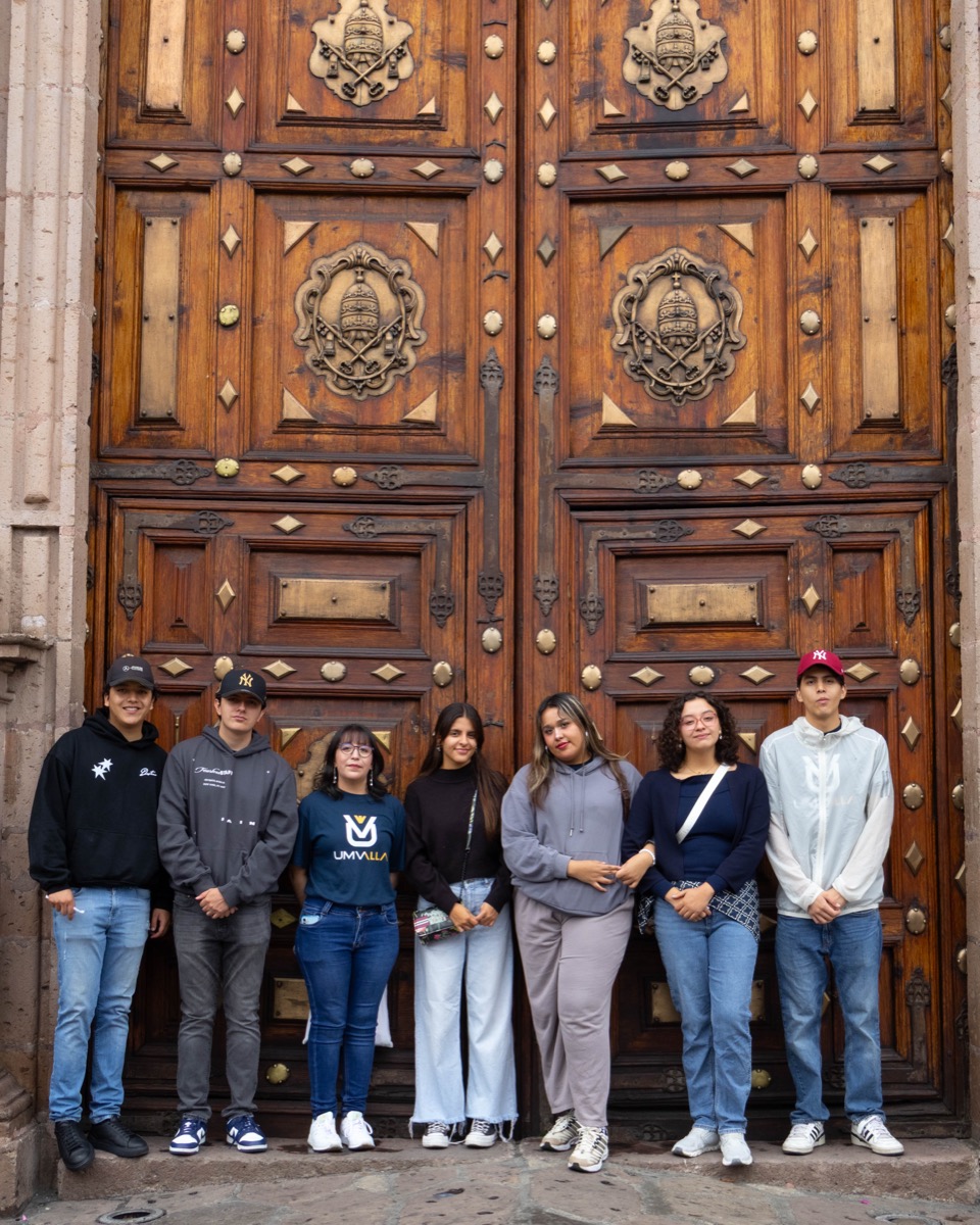 Estudiantes de UMValla frente a la puerta tallada de un edificio patrimonial.