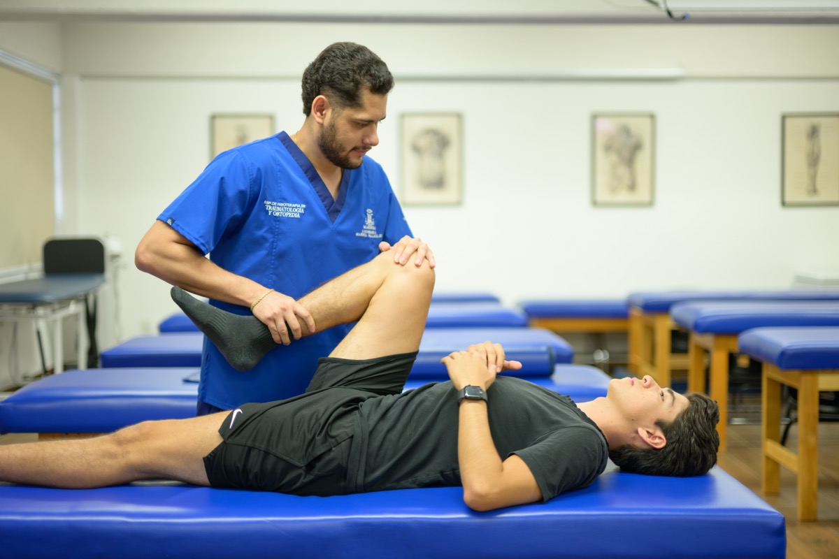 Estudiante de UMValla movilizando la rodilla de un paciente.