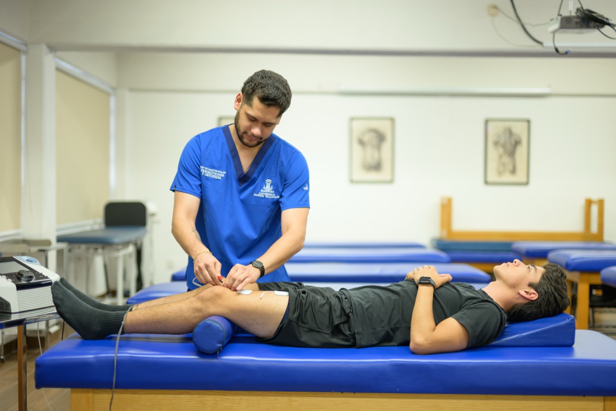 Estudiante de UMValla aplicando electroterapia en la camilla.